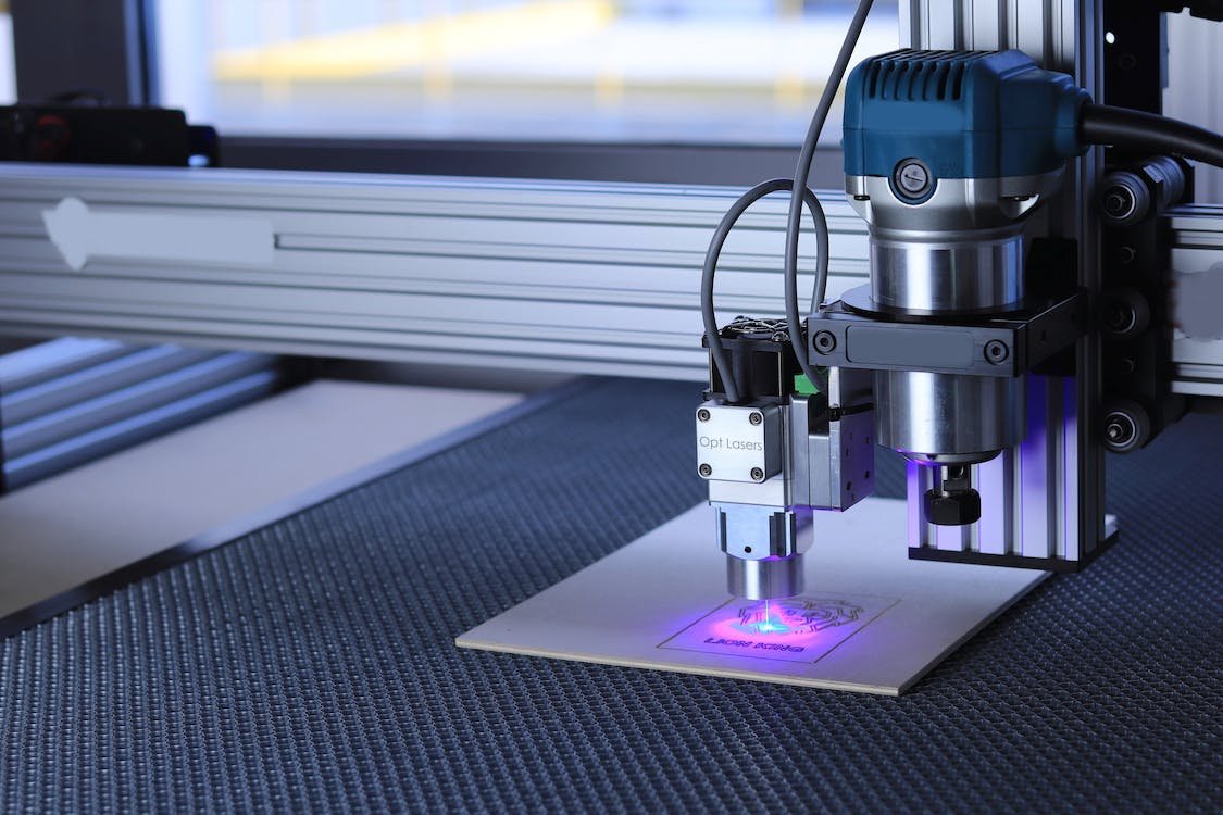 Máquina de corte a laser, em funcionamento, gravando uma placa de MDF, na fábrica da Imprima.vc